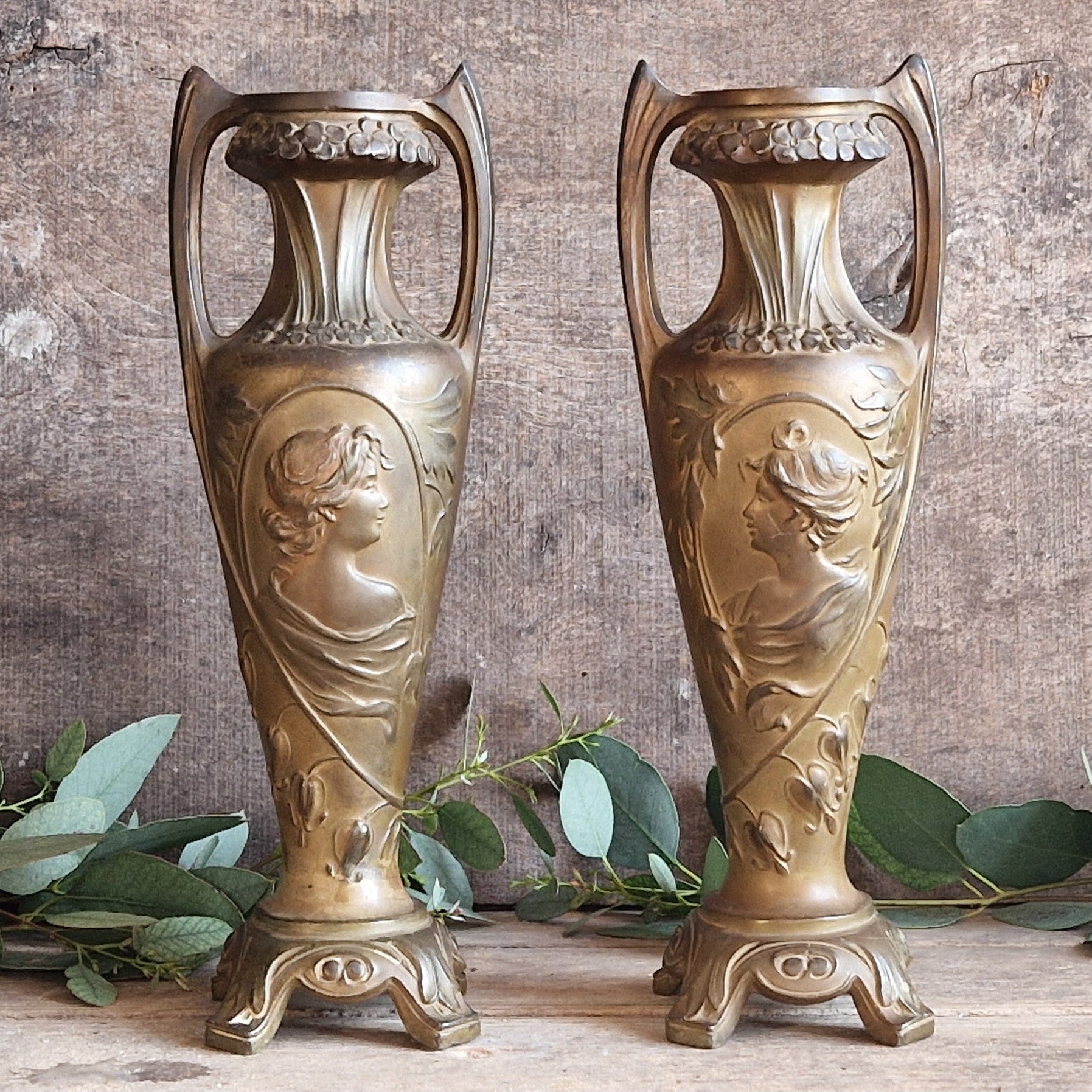 Two ornate bronze coloured spelter  vases with classical Art Nouveau designs.
