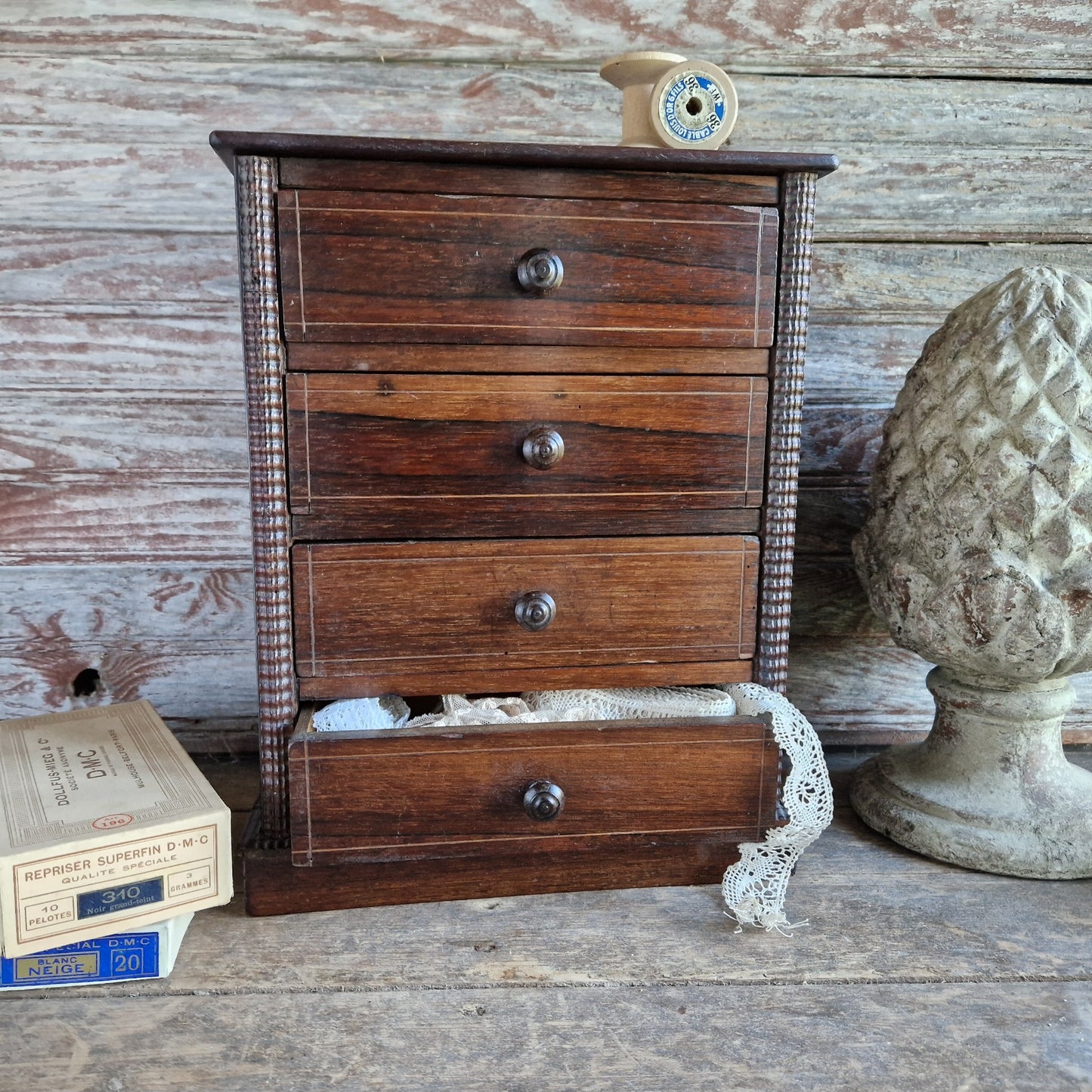 Small wooden chest of drawers with four drawers on a rustic surface