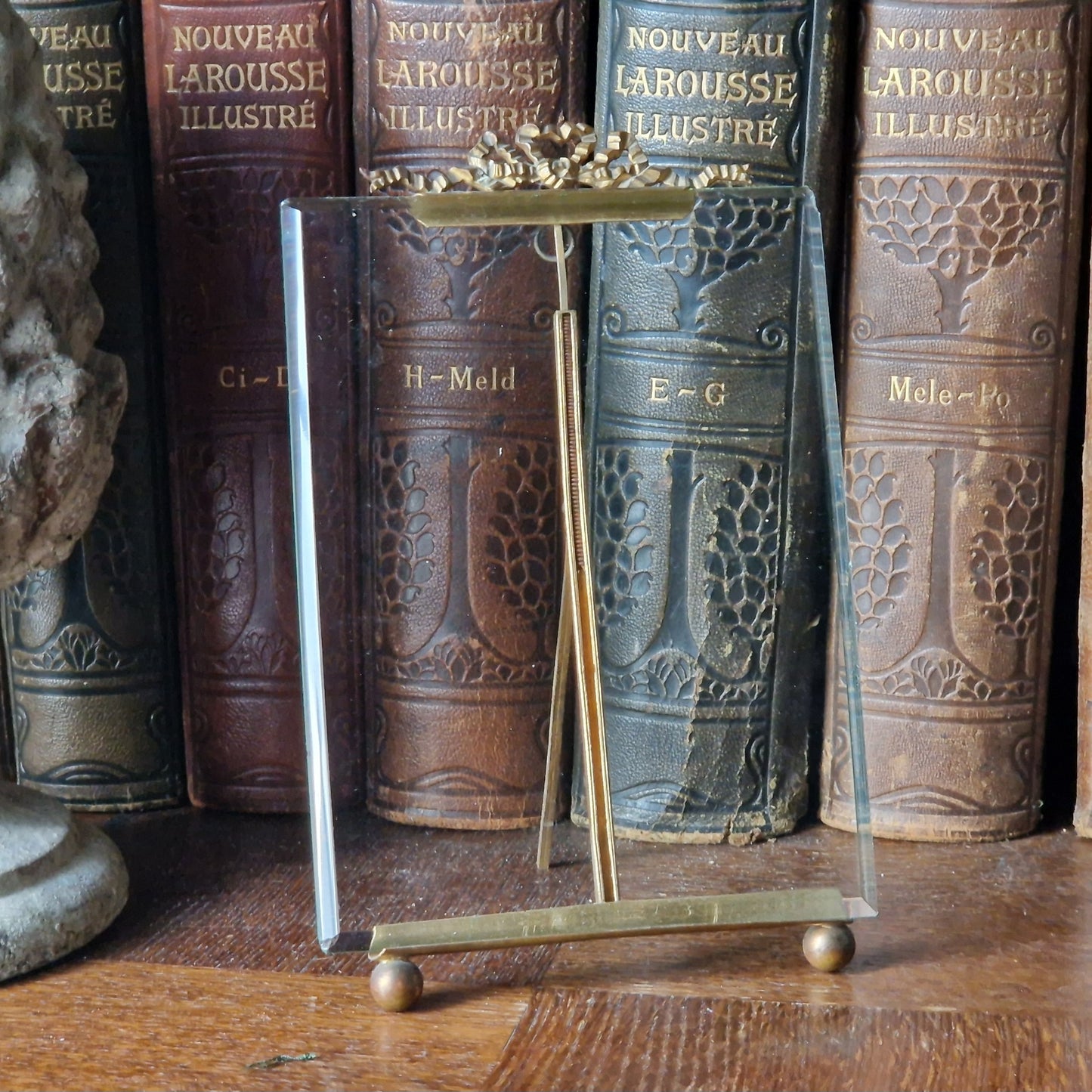 French antique glass photo frame with ribbon decoration in front of leather books.