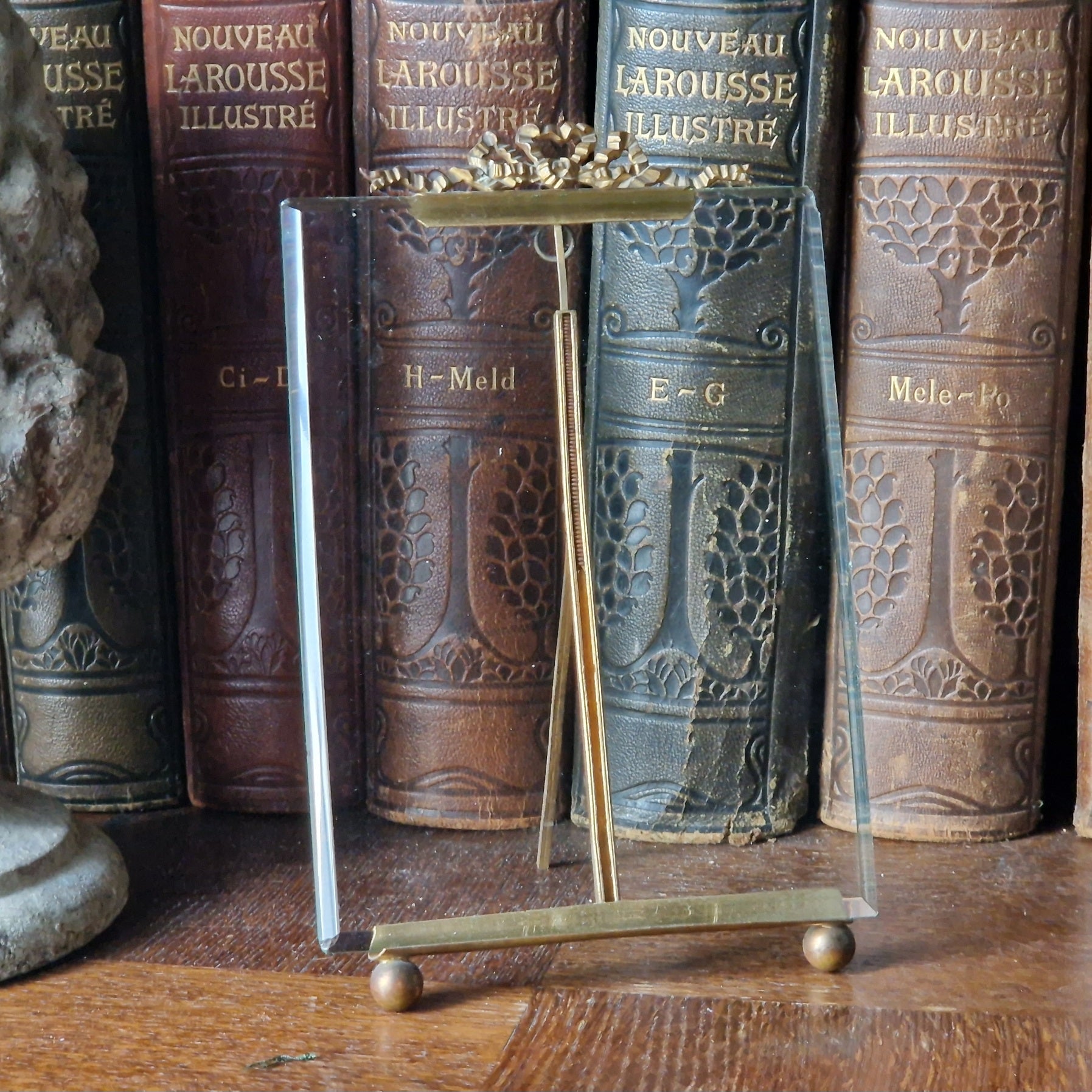 French antique glass photo frame with ribbon decoration in front of leather books.