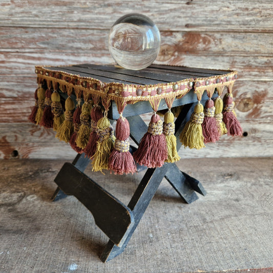 Small wooden table with tassels and a glass ball on a rustic wooden background