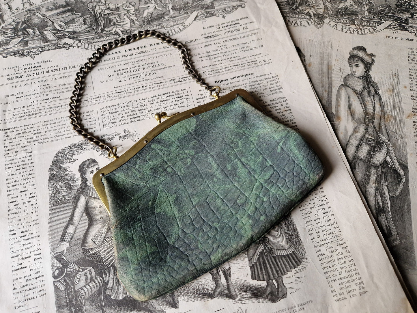 Green textured clutch bag on an open book with vintage illustrations