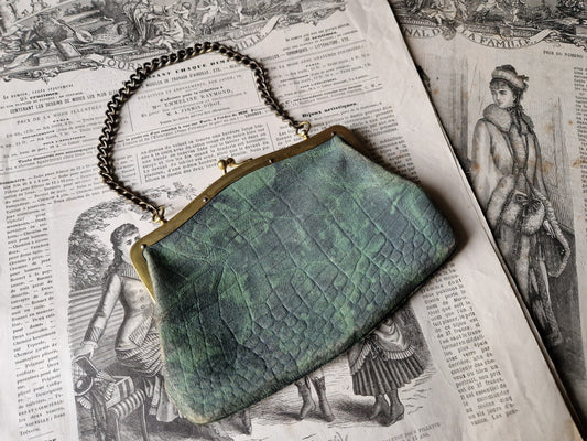 Green textured clutch bag on an open book with vintage illustrations