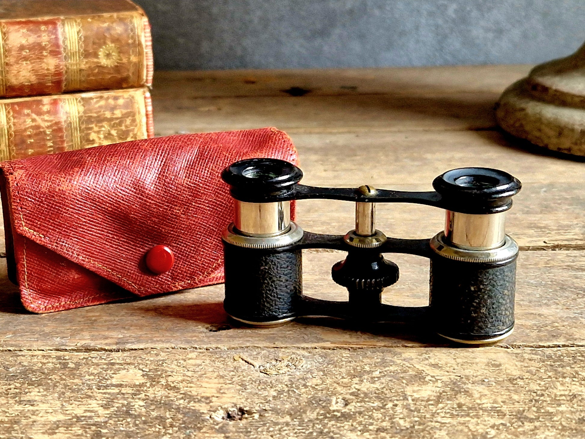 Vintage binoculars with a red case on a wooden surface
