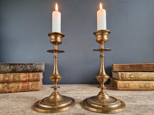 Pair of brass antique candle holders with candles.